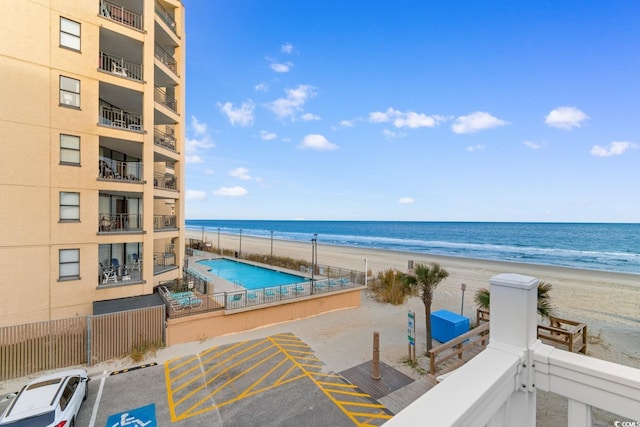 view of swimming pool with a water view and a beach view