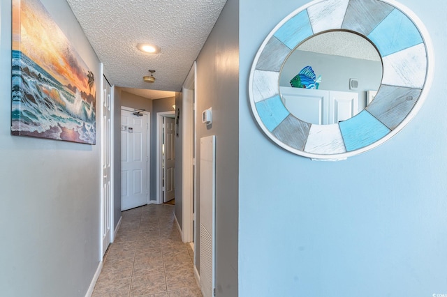 hall featuring light tile patterned floors and a textured ceiling