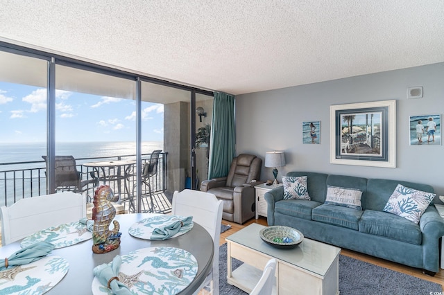 living room featuring plenty of natural light, expansive windows, a water view, and wood-type flooring