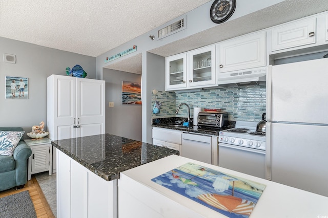 kitchen with backsplash, a textured ceiling, white appliances, extractor fan, and white cabinets