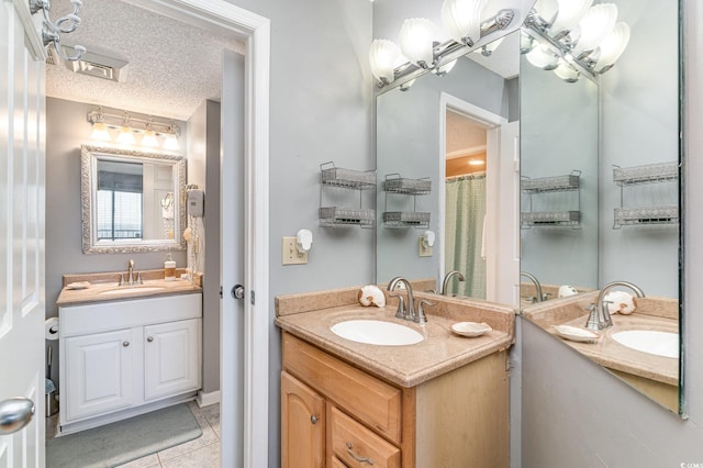 bathroom with tile patterned flooring, vanity, and a textured ceiling