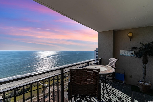 balcony at dusk with a water view and a beach view