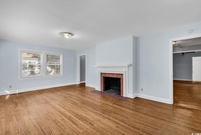 unfurnished living room with hardwood / wood-style floors and a brick fireplace