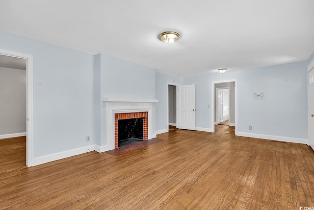 unfurnished living room with hardwood / wood-style floors and a brick fireplace