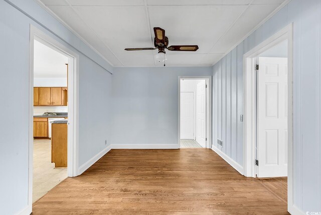 unfurnished room with ceiling fan, crown molding, and light wood-type flooring