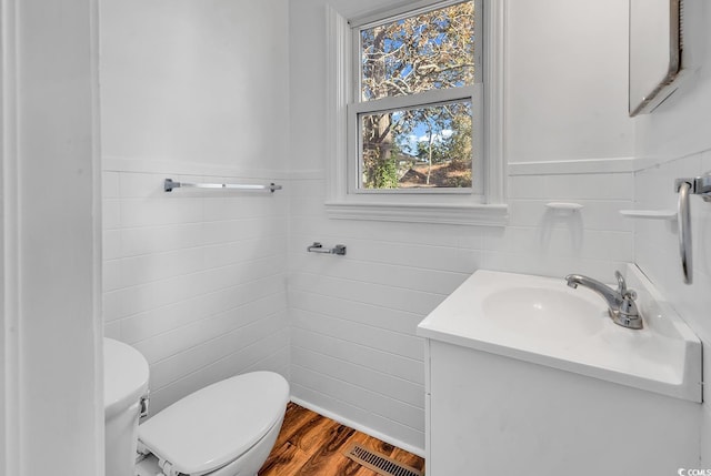 bathroom featuring hardwood / wood-style floors, vanity, toilet, and tile walls