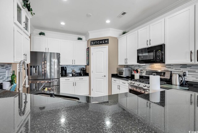 kitchen with backsplash, dark stone counters, ornamental molding, stainless steel appliances, and white cabinets