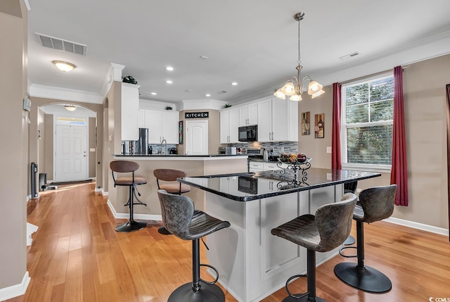 kitchen with a breakfast bar, light wood-type flooring, decorative light fixtures, and white cabinetry