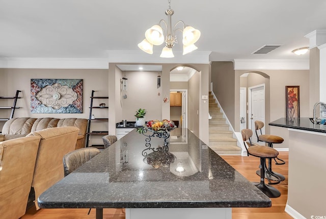 dining room featuring a notable chandelier, light wood-type flooring, and crown molding