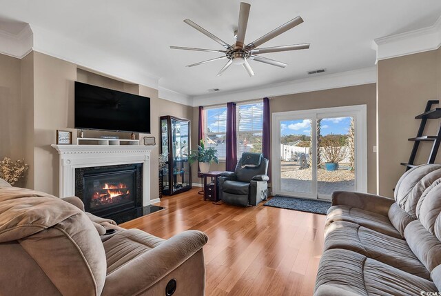 living room with ceiling fan, ornamental molding, and light wood-type flooring