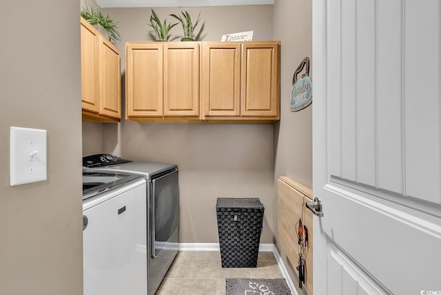 clothes washing area with cabinets, light tile patterned floors, and washer and dryer