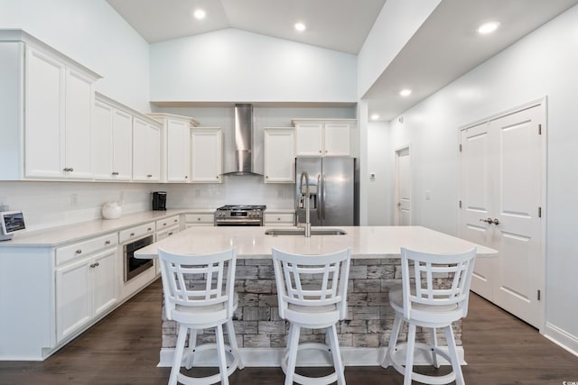 kitchen with a center island with sink, a breakfast bar, wall chimney range hood, and stainless steel appliances