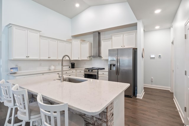 kitchen with sink, stainless steel appliances, wall chimney range hood, a kitchen bar, and a center island with sink