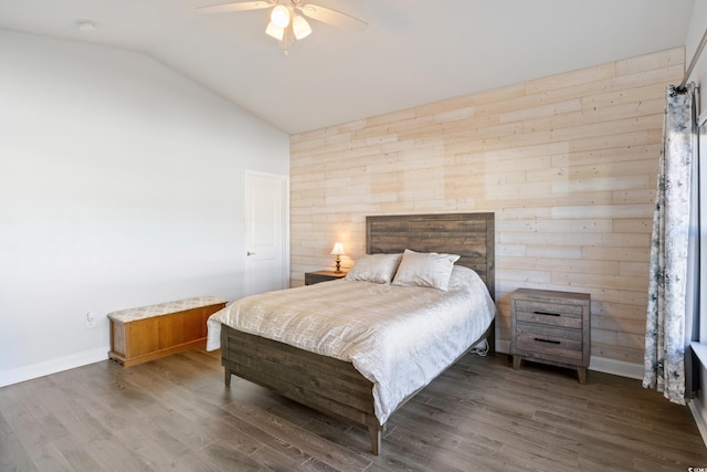 bedroom with dark hardwood / wood-style floors, ceiling fan, lofted ceiling, and wood walls