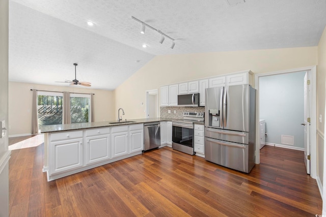 kitchen with kitchen peninsula, stainless steel appliances, white cabinets, and sink