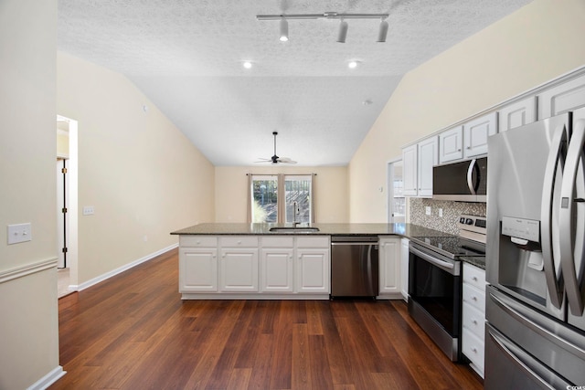 kitchen with lofted ceiling, white cabinets, a textured ceiling, kitchen peninsula, and stainless steel appliances