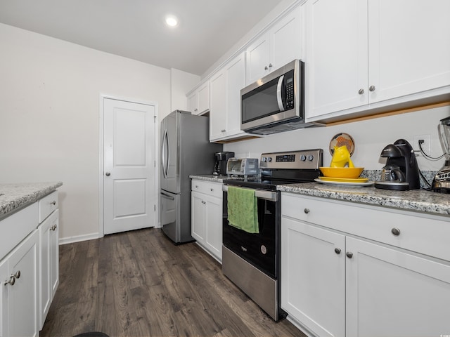 kitchen with white cabinets, dark hardwood / wood-style floors, light stone counters, and appliances with stainless steel finishes