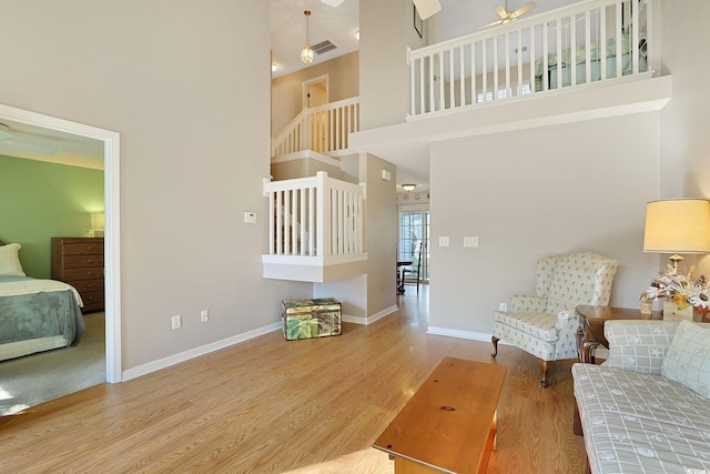 living room featuring light wood-type flooring, a towering ceiling, and ceiling fan