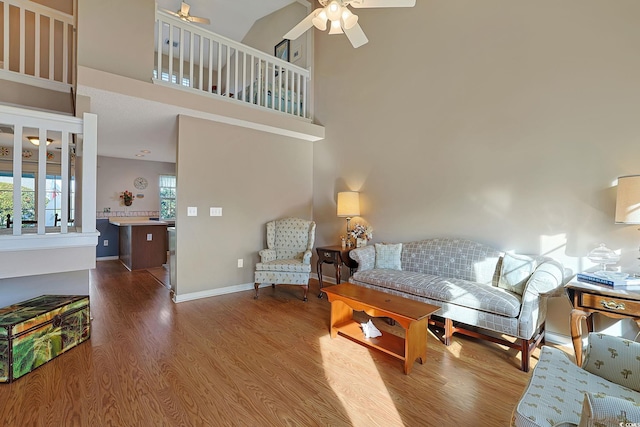 living room with ceiling fan, wood-type flooring, and a high ceiling