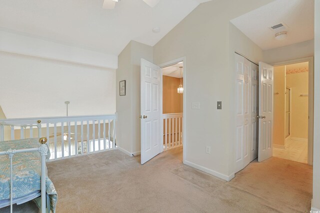 corridor with light carpet and lofted ceiling