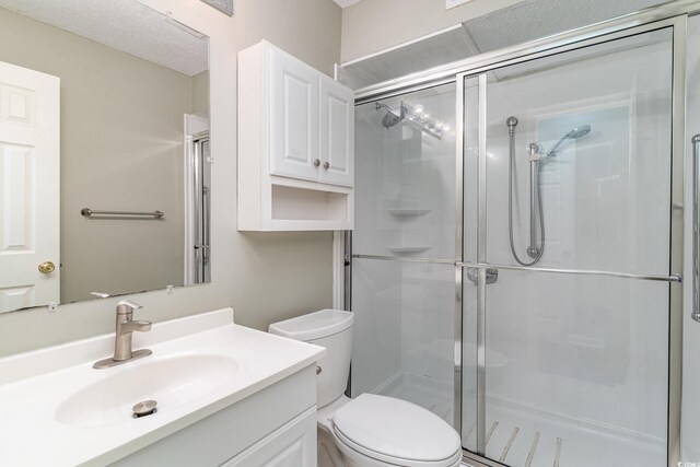 bathroom featuring vanity, a shower with shower door, and toilet