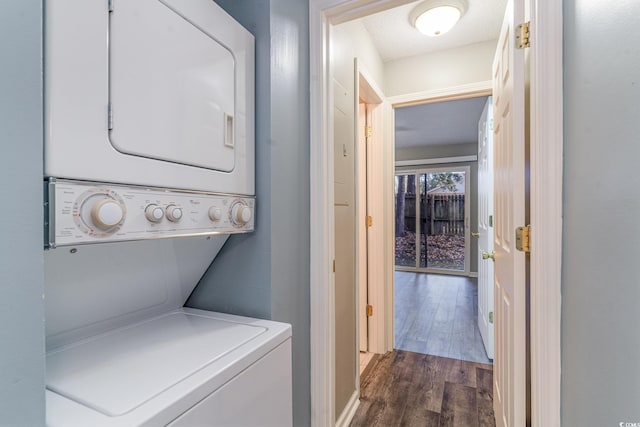 clothes washing area with stacked washer / drying machine, dark hardwood / wood-style flooring, and a textured ceiling