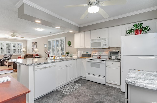 kitchen with light stone countertops, sink, kitchen peninsula, white appliances, and white cabinets