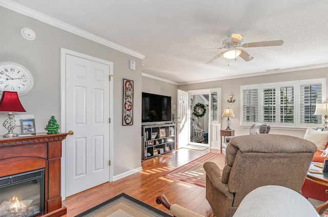 living room featuring ceiling fan, light hardwood / wood-style flooring, a textured ceiling, and ornamental molding