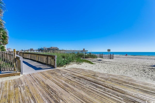 dock area with a water view and a beach view