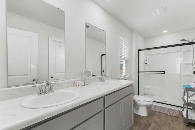 bathroom with toilet, vanity, a shower with shower door, and hardwood / wood-style flooring