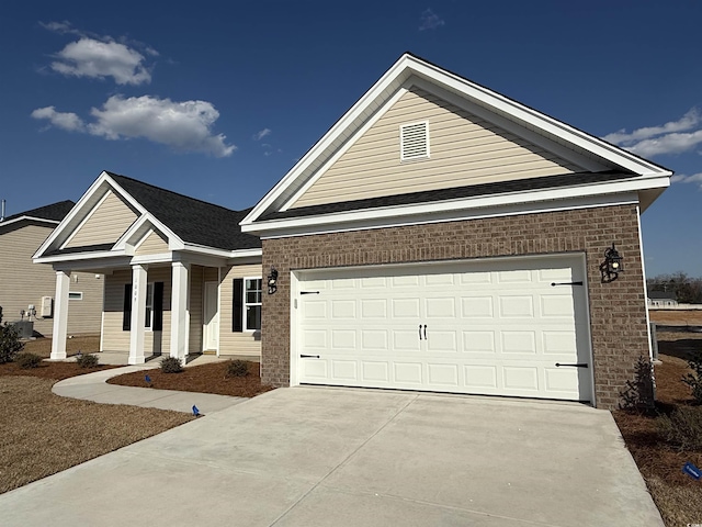 view of front of house featuring a porch, concrete driveway, an attached garage, and brick siding