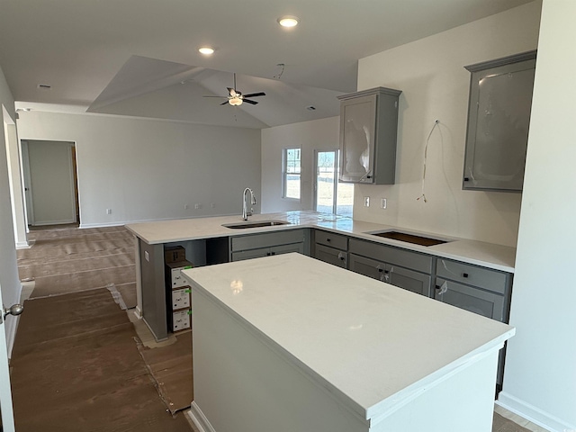 kitchen with a sink, black electric cooktop, a peninsula, and gray cabinets