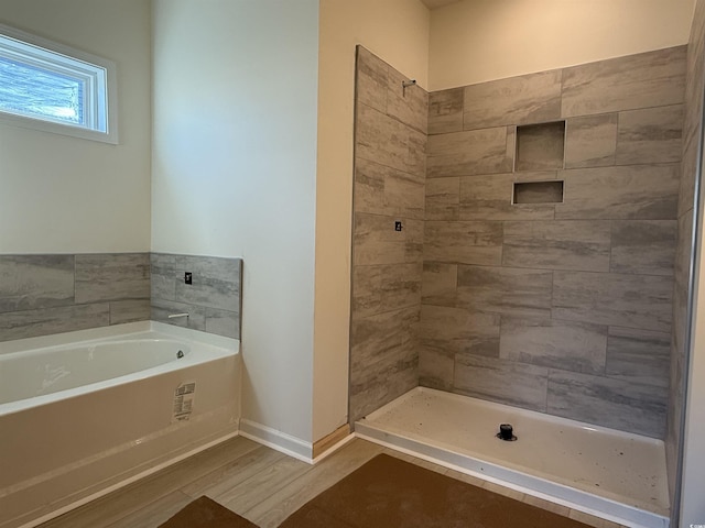 bathroom featuring baseboards, a garden tub, wood finished floors, and a tile shower