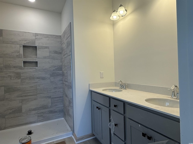 full bath with double vanity, tiled shower, and a sink