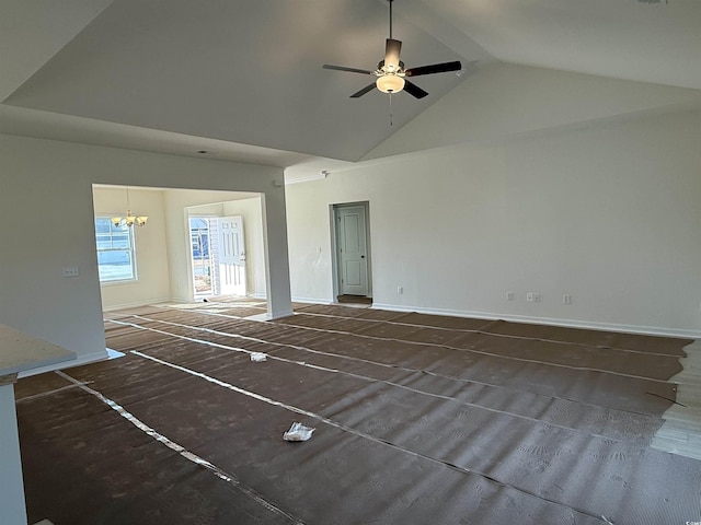 unfurnished living room with ceiling fan with notable chandelier, baseboards, and high vaulted ceiling