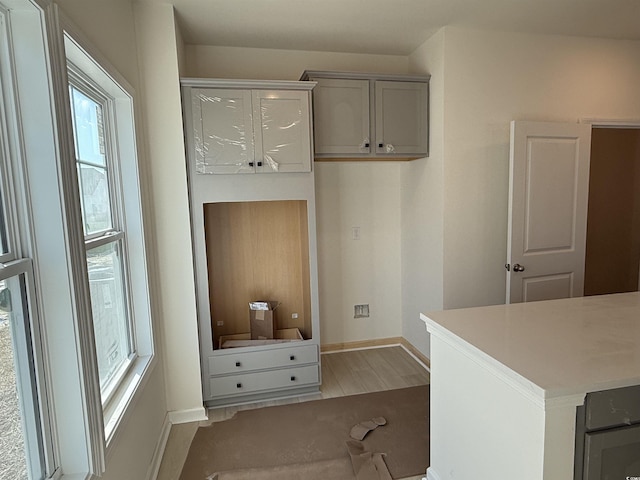 interior space featuring baseboards, light wood-style floors, gray cabinets, and light countertops