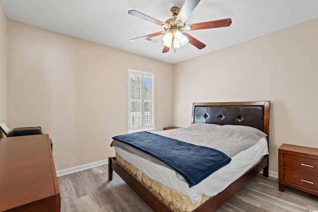 bedroom featuring ceiling fan, light hardwood / wood-style floors, and a textured ceiling