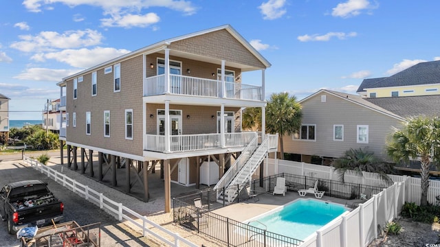 back of property featuring a balcony, a fenced in pool, and a patio