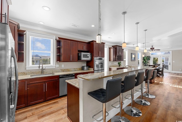 kitchen with stainless steel appliances, ceiling fan, sink, pendant lighting, and a kitchen island