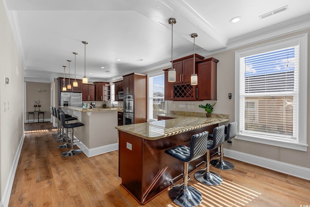 kitchen featuring kitchen peninsula, a breakfast bar, stainless steel appliances, pendant lighting, and a kitchen island