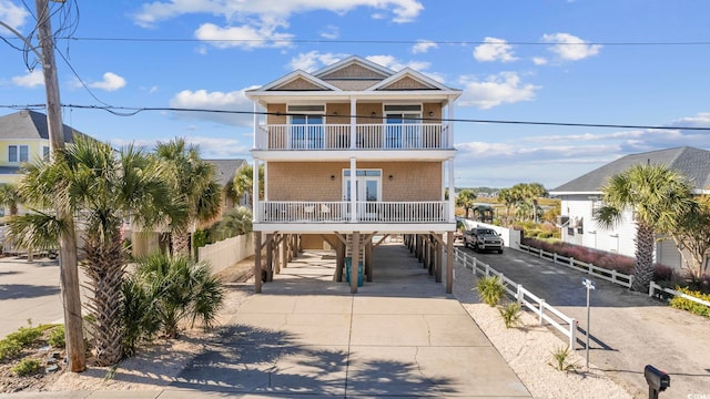 raised beach house featuring a balcony and a carport