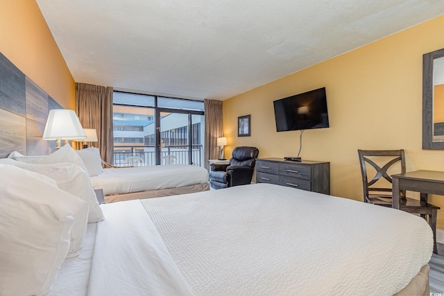 bedroom featuring access to exterior, a textured ceiling, and a wall of windows