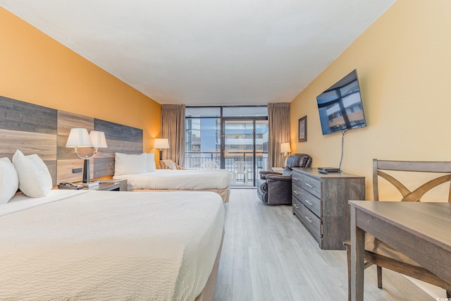 bedroom featuring expansive windows, access to exterior, and light wood-type flooring