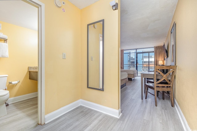 corridor with a textured ceiling and light wood-type flooring