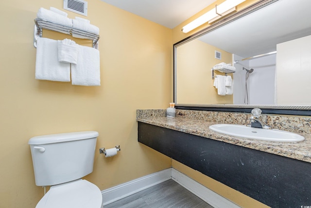 bathroom featuring a shower, hardwood / wood-style floors, vanity, and toilet