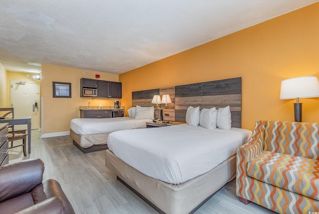 bedroom featuring a textured ceiling and light hardwood / wood-style flooring