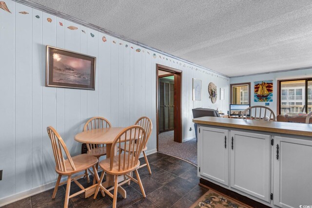 tiled dining area featuring a textured ceiling and wooden walls