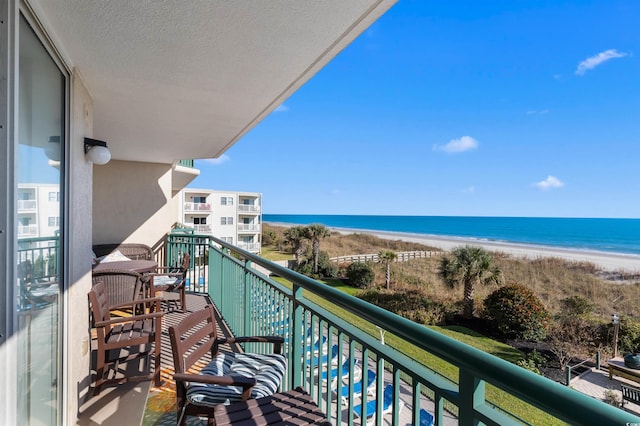 balcony with a water view and a view of the beach