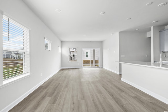 unfurnished living room with sink and light hardwood / wood-style flooring