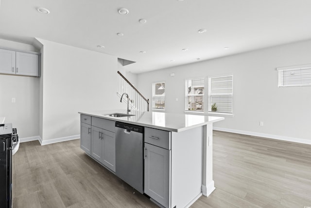 kitchen with sink, appliances with stainless steel finishes, gray cabinets, and a kitchen island with sink